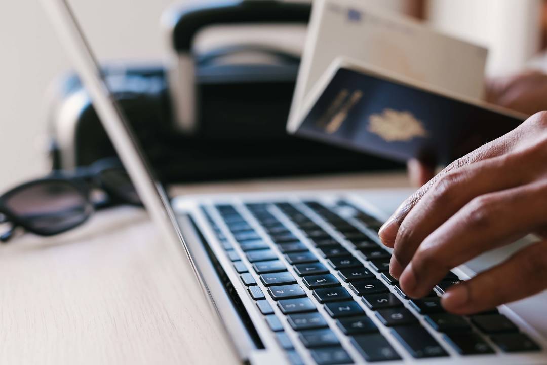 person_booking_trip_laptop_passport_online_registration.jpg